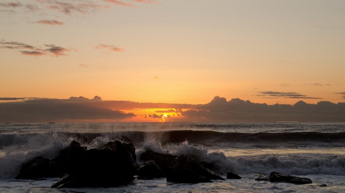 Ocean waves crashing on rocks at sunset
