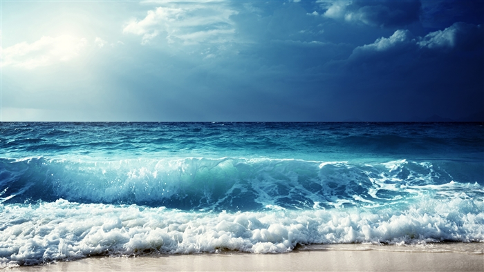 Ocean waves crashing on a sandy beach under a cloudy sky