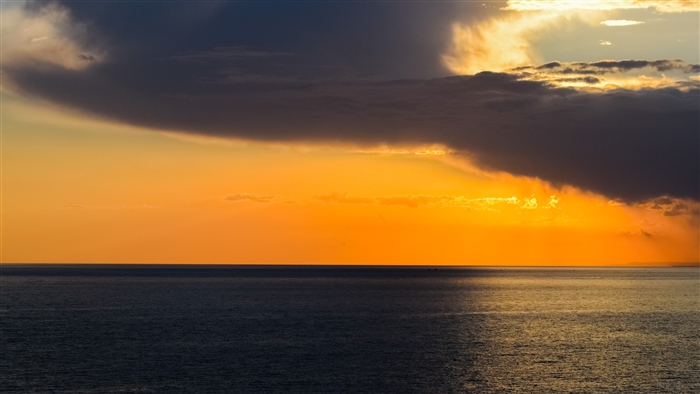 Sunset over the ocean with dark clouds