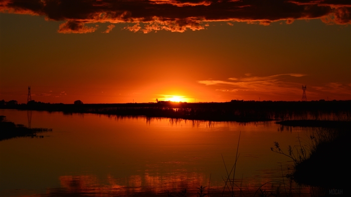 Sunset over a body of water with power lines