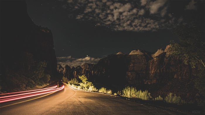 Night road with light trails and mountains