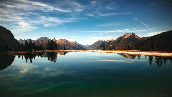 Lake reflection of mountains and forest under blue sky
