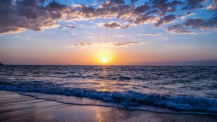 Sunset over the ocean with clouds and waves