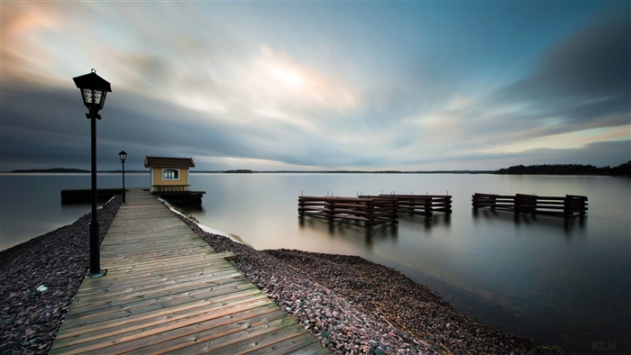 Wooden pier with a small house and lampposts on a lake