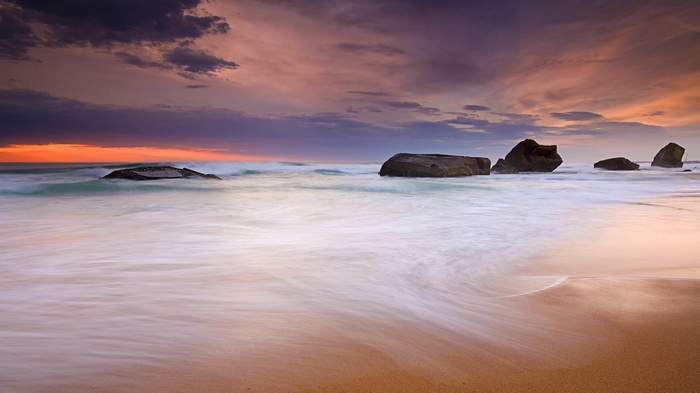 Ocean waves crash on rocks at sunset