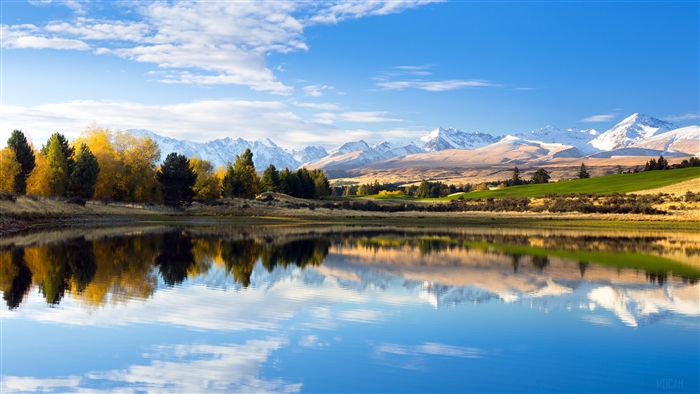Lake reflection of autumn trees and snow-capped mountains