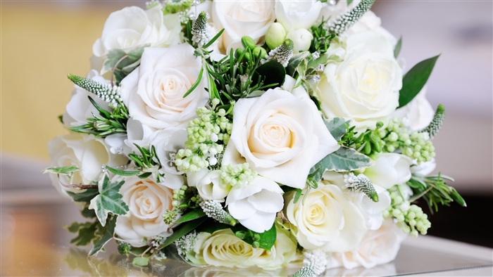 White roses bouquet with green leaves on a reflective surface