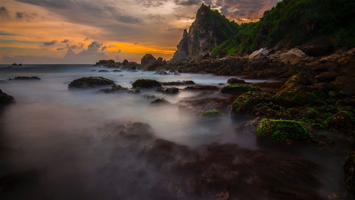 Rocky Coastline with Misty Ocean and Mountain at Sunset 4K