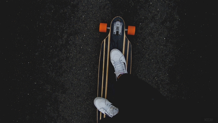 Longboard skateboard with orange wheels and person's legs