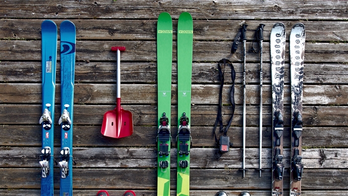 Skis, poles, and shovel on wooden background