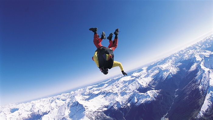 Two skydivers freefalling over snowy mountains 4K