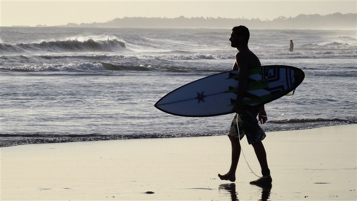 Surfer walking on Bali beach with surfboard