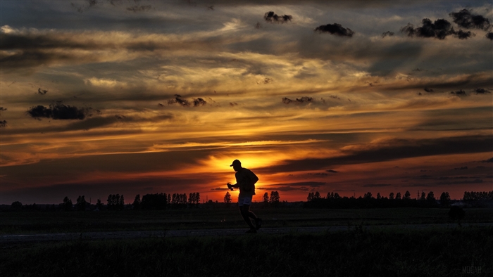 Silhouette of a runner at sunset with clouds