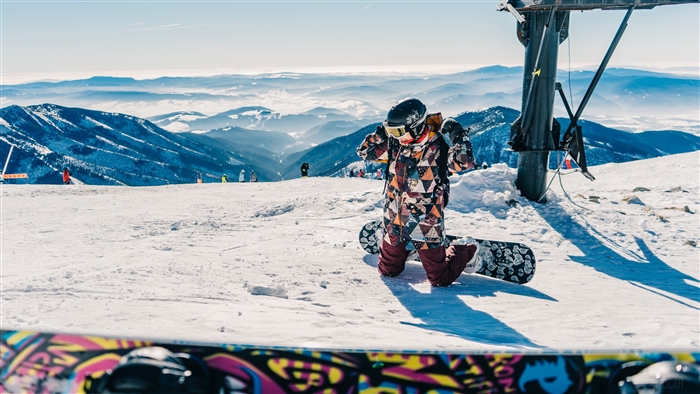 Snowboarder adjusting goggles on snowy mountain