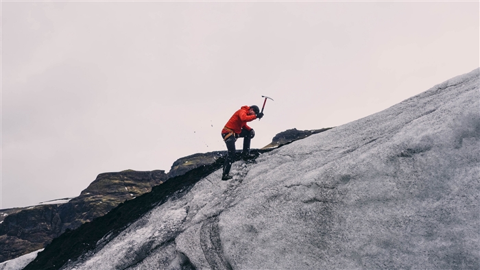Man climbing icy mountain with ice axe