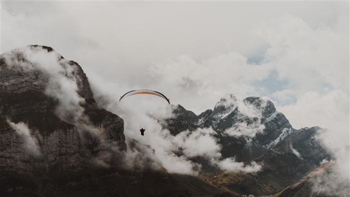 Paraglider flying over misty mountains