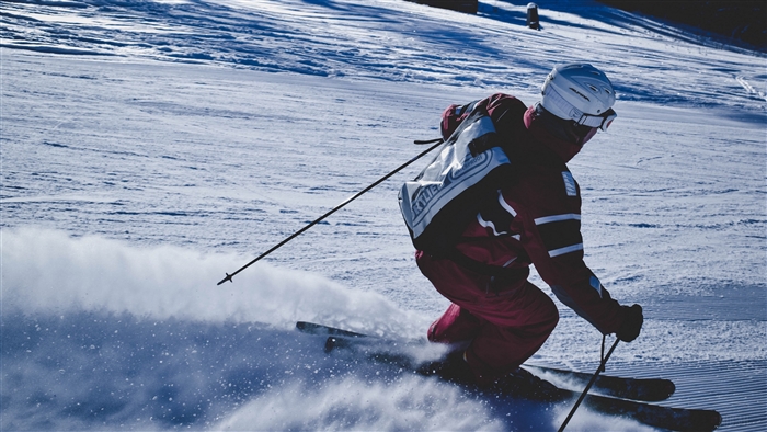 Skier in red suit skiing down a snowy slope