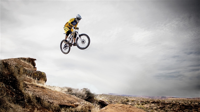 Mountain biker performing a jump over a rocky terrain
