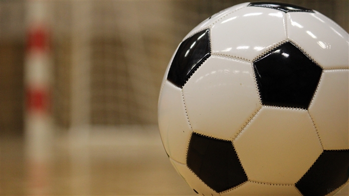 Soccer ball on wooden floor with goal net