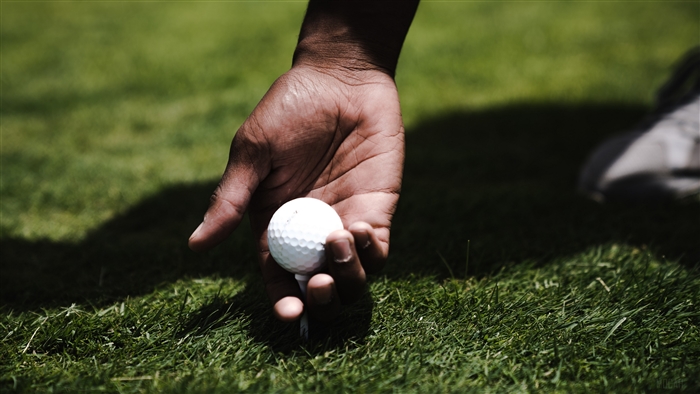 Hand placing golf ball on tee on grass 4K
