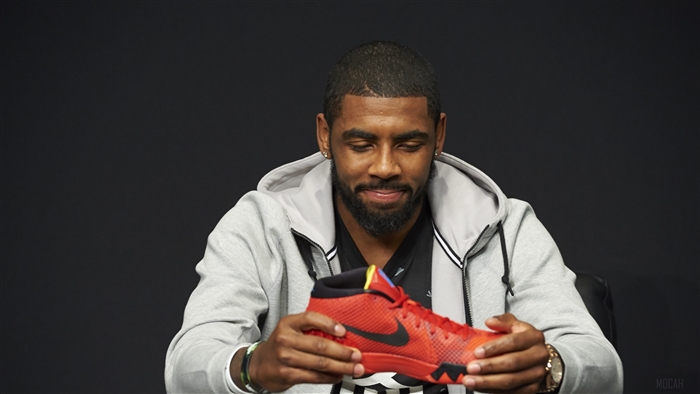 Kyrie Irving holding a red Nike basketball shoe