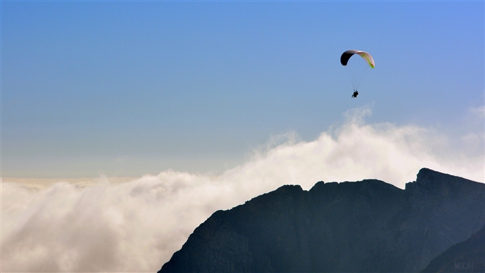 Paraglider flying over mountains above clouds 4K