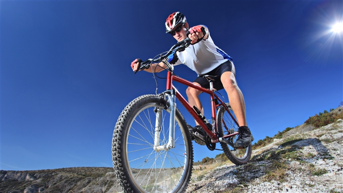 Mountain biker riding on a rocky trail under a clear blue sky