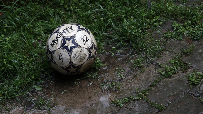 Soccer ball on wet ground with grass
