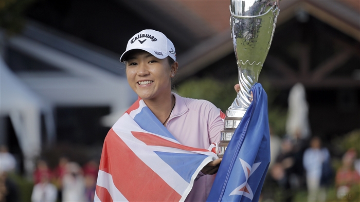Lydia Ko holding trophy with flags
