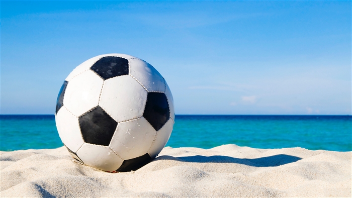 Soccer ball on a sandy beach with ocean and sky