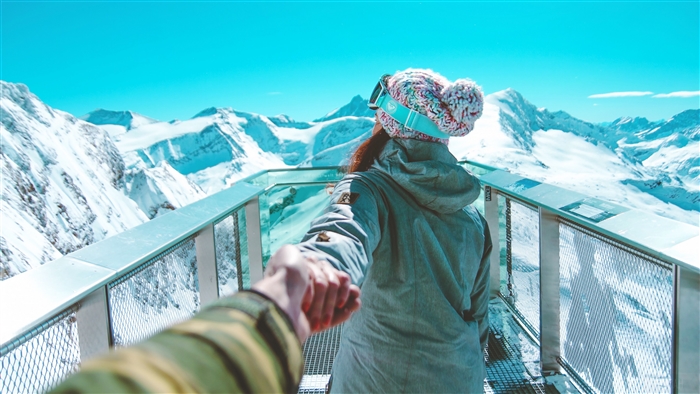 Couple holding hands on a snowy mountain observation deck 4K