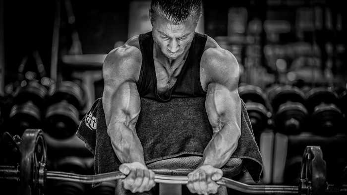 Bodybuilder performing bicep curls with a barbell