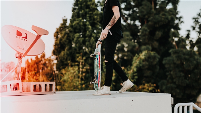 Skateboarder with tattoos holding a skateboard