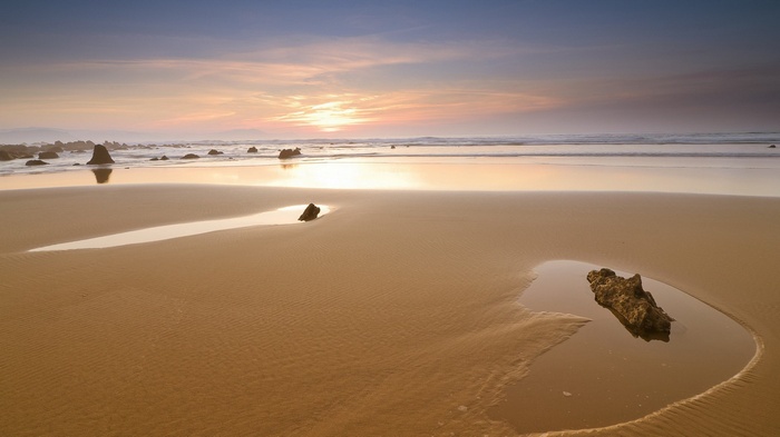 Beach with tide pools and rocks at sunset