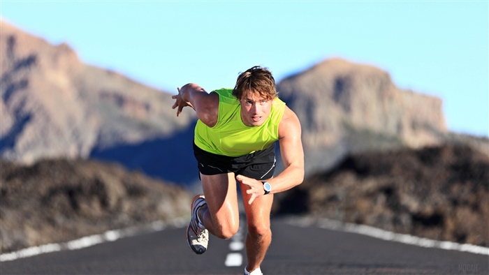 Man running on a road with mountains in the background