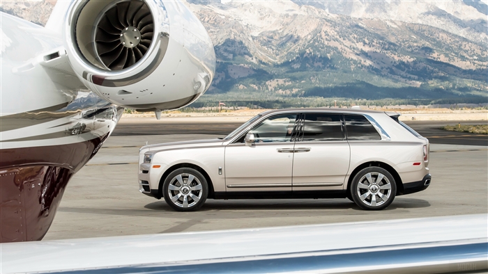 Rolls Royce Cullinan parked by a private jet