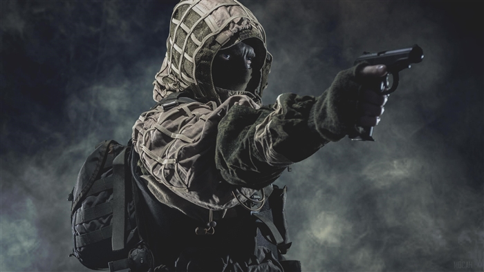 Soldier in ghillie suit aiming a pistol