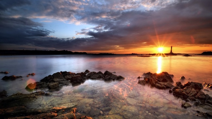 Sunset over the ocean with a lighthouse