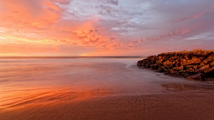 Sunset over the ocean with a rocky shore