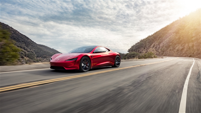 Red 2018 Tesla Roadster driving on a winding road