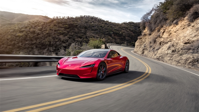Red Tesla Roadster driving on a winding road