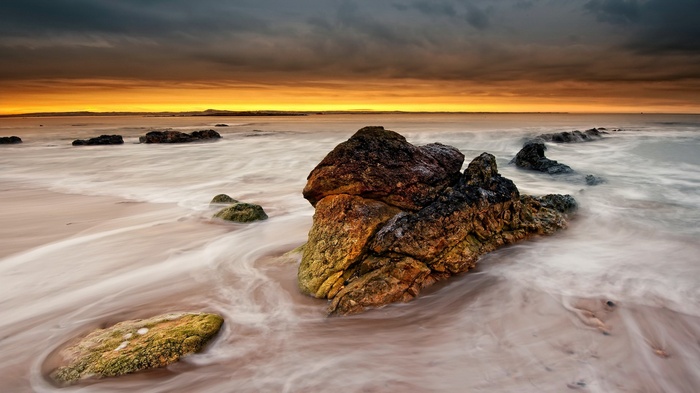 Rocky beach with waves at sunset