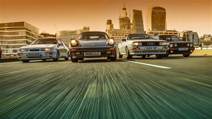 Four classic cars driving on a road with city skyline