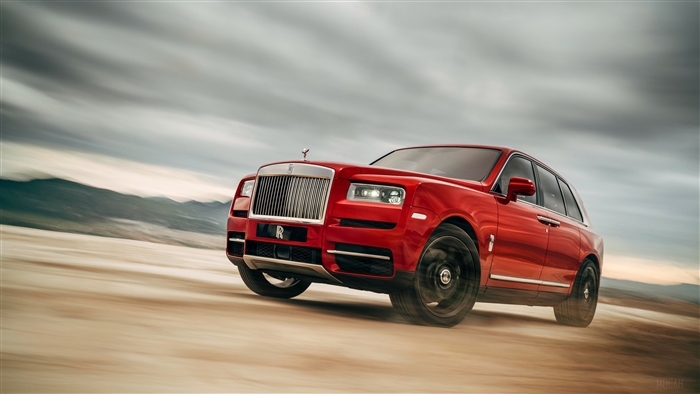 Red Rolls Royce Cullinan SUV driving on dirt road