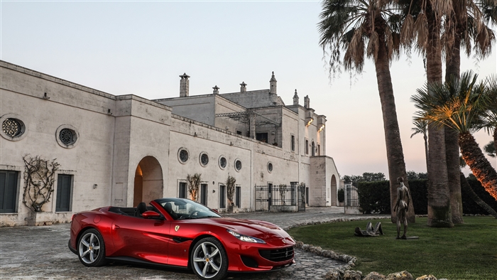 Red Ferrari Portofino convertible parked in front of a villa