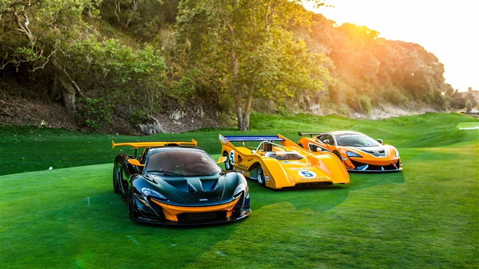Three McLaren sports cars on a golf course