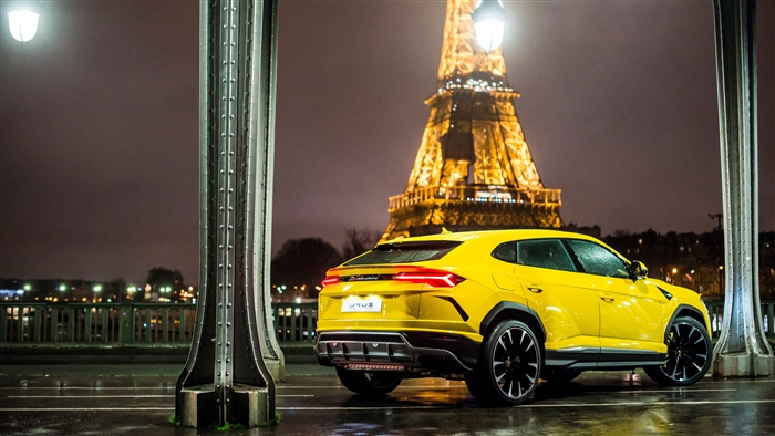 Yellow Lamborghini Urus parked near Eiffel Tower at night