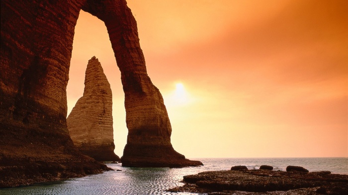 Arch rock formation over the ocean at sunset