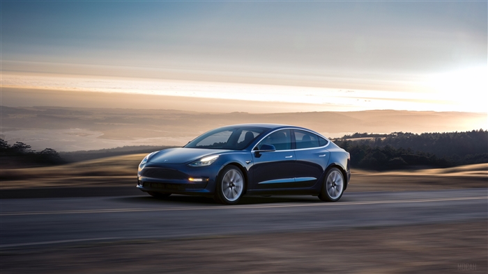 Blue 2017 Tesla Model 3 driving on a road