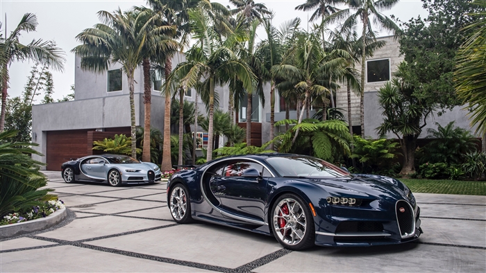 Two Bugatti Chirons parked in front of a modern house